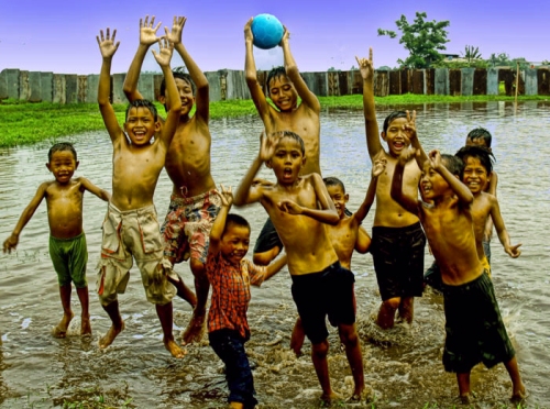Kubangan air banjir menjadi sarana anak-anak bermain dengan gembira. Mereka tertawa, bercanda dan 