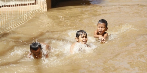 Anak-anak selalu bergembira bisa ciblon air banjir, sekalipun banjir belum surut.