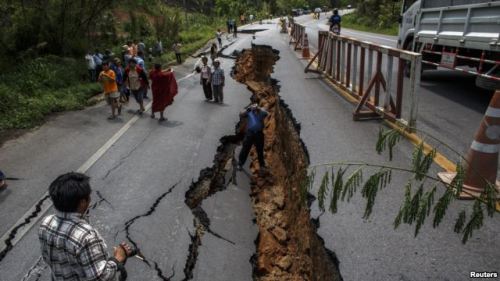 Warga di Chiang Rai, bagian utara Thailand, melintasi jalanan yang rusak akibat gempa (6/5). Gempa bumi berkekuatan 6SR mengguncang wilayah ini hari Senin, 5 Mei 2014.