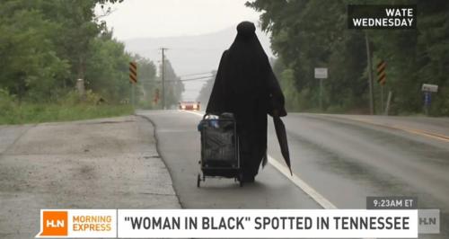 Wanita berpakaian hitam berjalan lamban seakan menuju alamat tak jelas yang dicarinya.