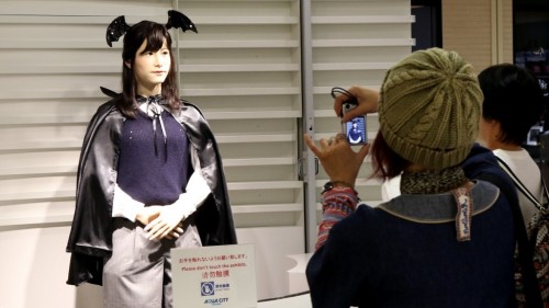 Robot humanoid Chihira Junko ( L ) , mengenakan kostum Halloween , menyapa pelanggan yang asyik memotretnya.
