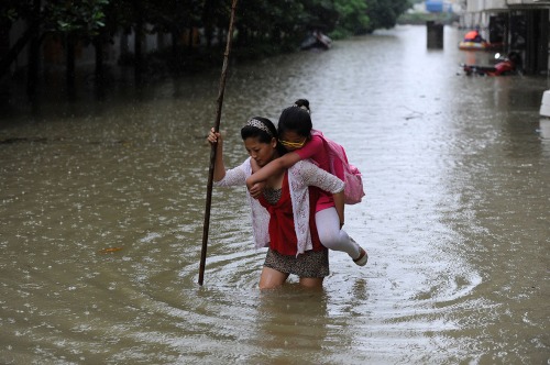 Ibu tengah menggendong anaknya melintasi genangan air kota Wuhan. 